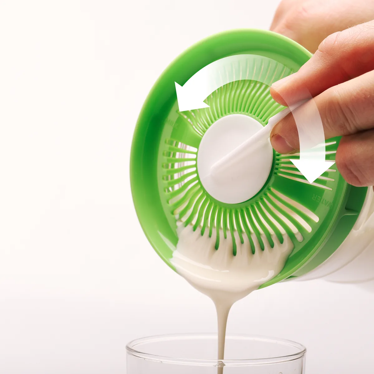 Kefir mit Hilfe des Schabers durch den Siebdeckel abgießen